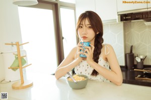 A woman sitting on the floor eating a bowl of noodles.