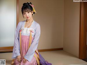 A woman in a blue and pink hanbok is posing for a picture.