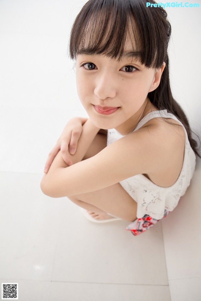 A young woman sitting on the floor with her arms crossed.