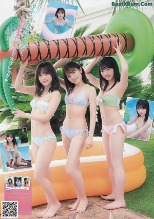 A group of three women in bikinis sitting on a beach.