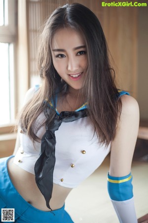 A woman in a blue skirt and white top posing for a picture.