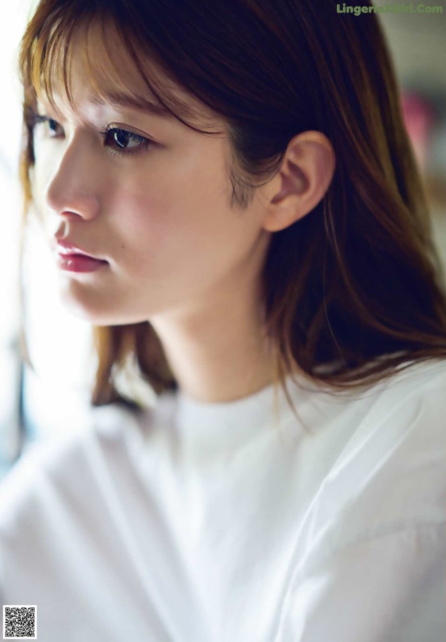 A woman with long brown hair wearing a white shirt.