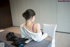 A woman in a purple bra and black pantyhose sitting on a white chair.