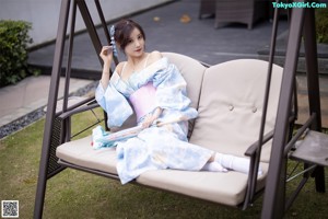 A woman in a blue and white kimono holding an umbrella.