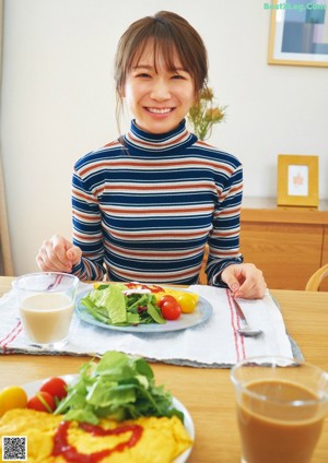 A woman wearing a brown sweater and a white scarf.