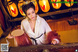 A woman sitting on a red chair holding a sword.