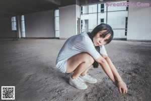 A woman sitting on the ground with her legs crossed.