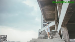 A woman in a white dress standing on some steps.
