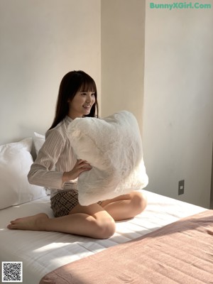 A woman sitting on top of a white table next to a plant.