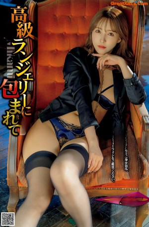 A woman in a black lingerie laying on a brown couch.