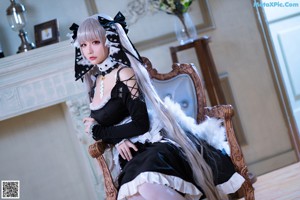 A woman in a maid outfit sitting on a chair.