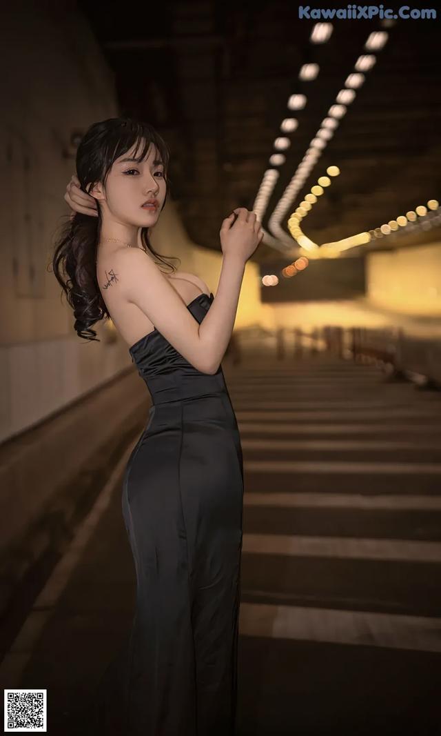 A woman in a black dress standing in a tunnel.