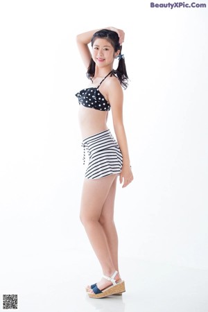 A woman in a black and white polka dot bikini top and striped skirt.