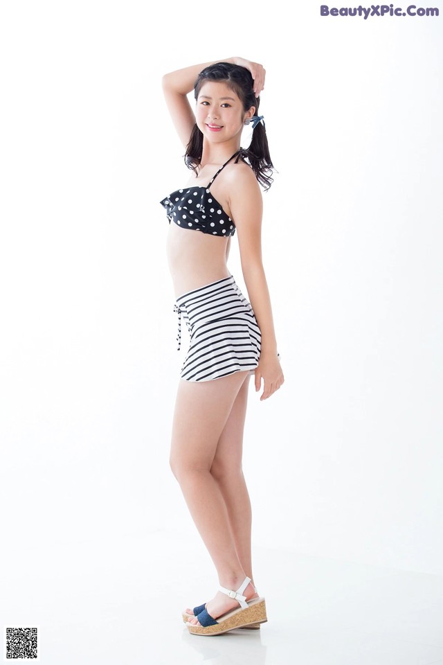 A woman in a black and white polka dot bikini top and striped shorts.