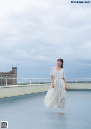 A woman in a white dress sitting on a bench.