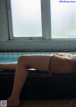 A naked woman laying in a pool of water.