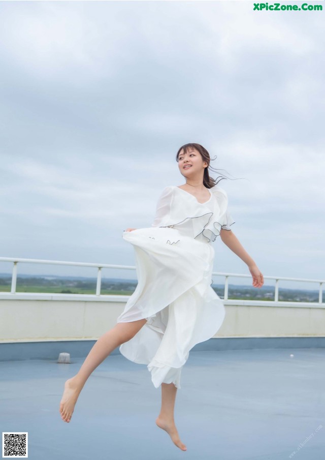 A woman in a white dress is jumping in the air.