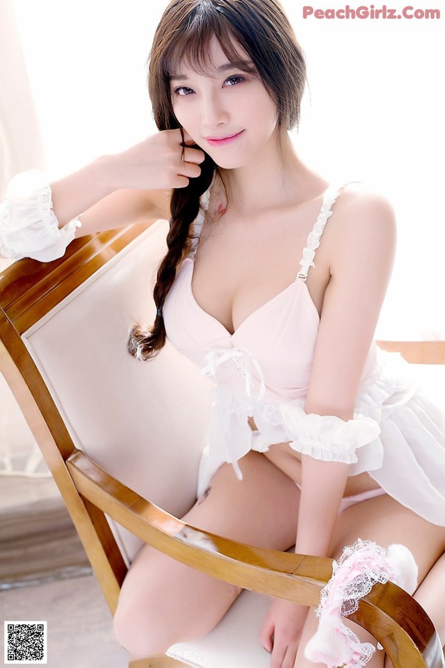 A woman in a white lingerie sitting on a chair.