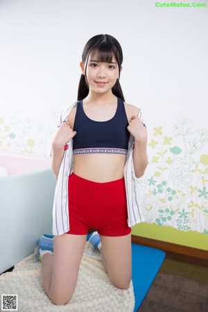 A woman in red shorts and a black top posing for a picture.