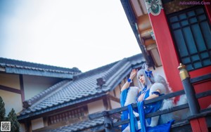 A woman in a blue and white outfit sitting on a chair.