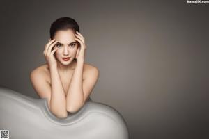 A nude woman sitting on the edge of a swimming pool.