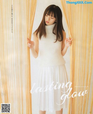 A woman sitting on a window sill in a white dress.