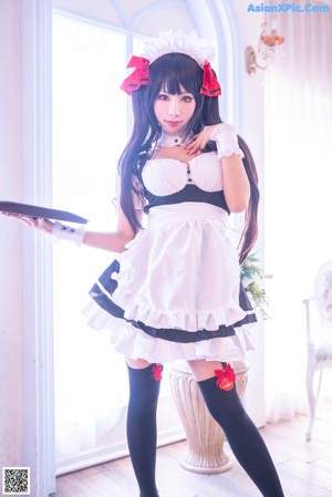 A woman dressed in a maid outfit posing for a picture.