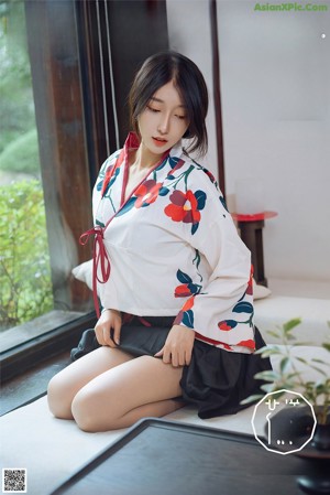 A woman sitting on a couch wearing a black bra and skirt.