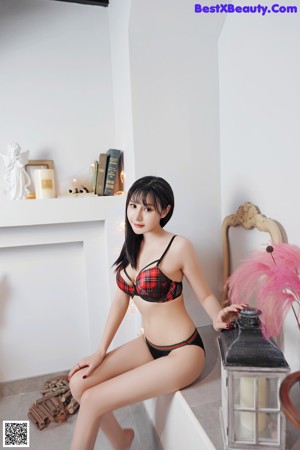 A woman in a red and black lingerie posing for a picture.