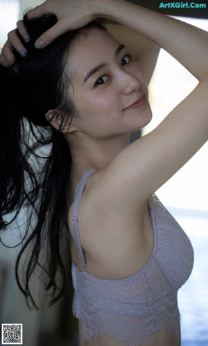 A woman in a blue bra and panties leaning against a wall.