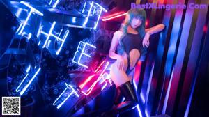 A woman in a black bodysuit and thigh high boots posing in front of a neon sign.