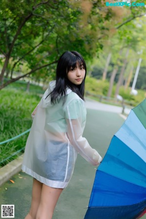 A woman in a raincoat holding an umbrella.