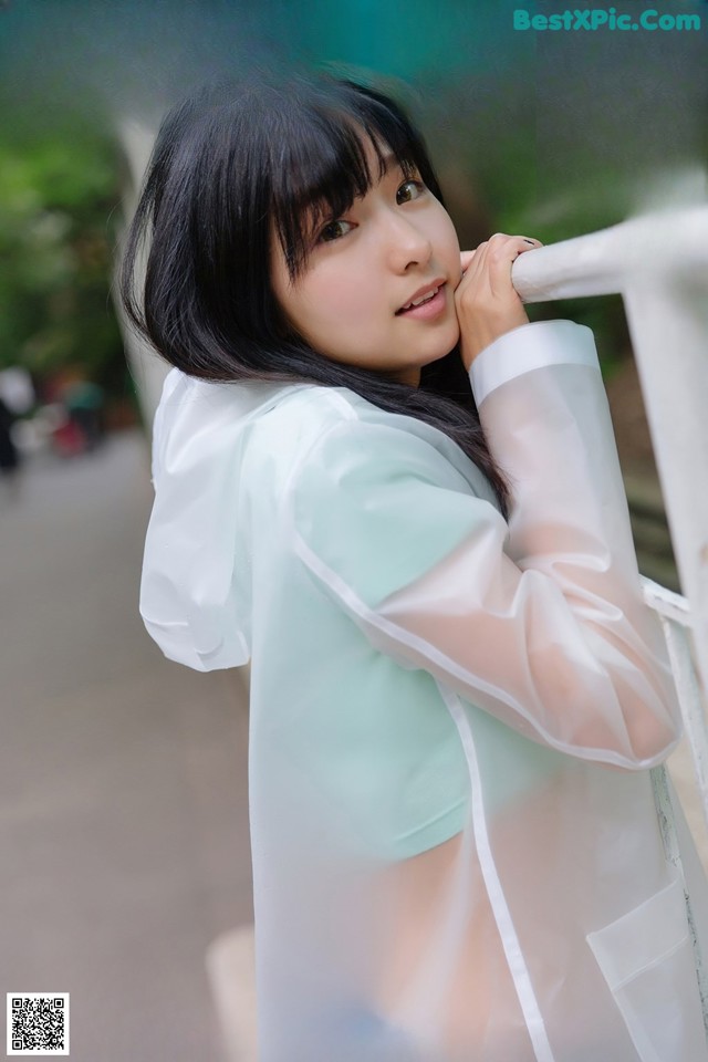 A woman in a white shirt leaning against a fence.