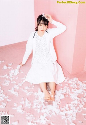 A woman sitting on top of a bed holding a white balloon.