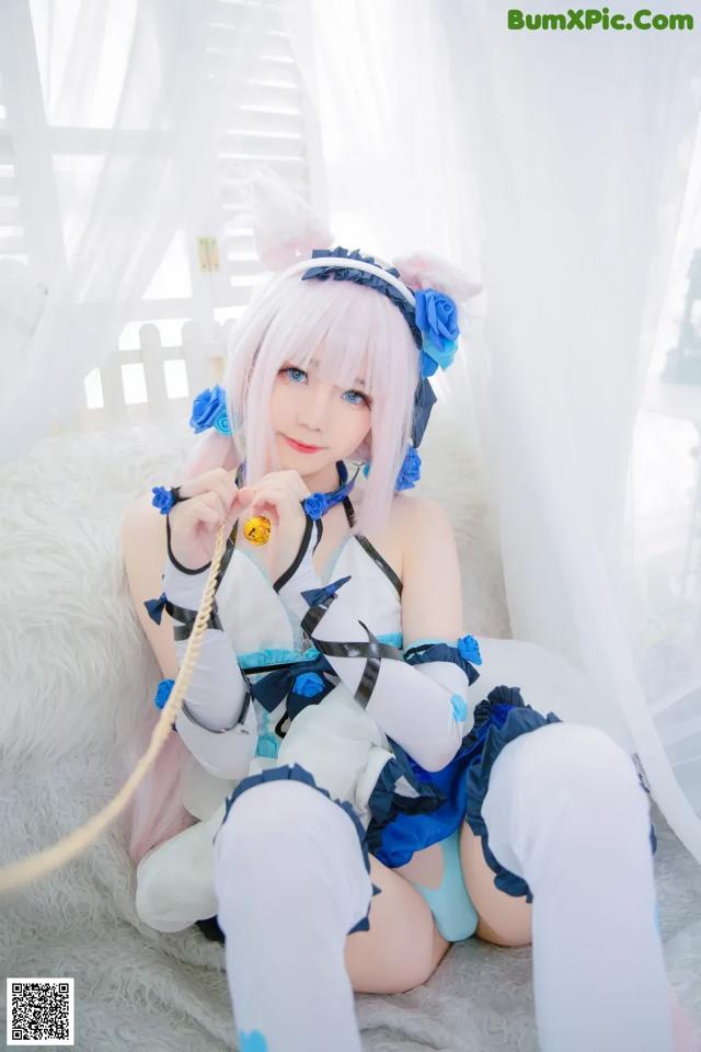 A woman in a blue and white outfit sitting on a bed.