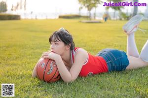 A woman sitting on the grass holding a basketball.