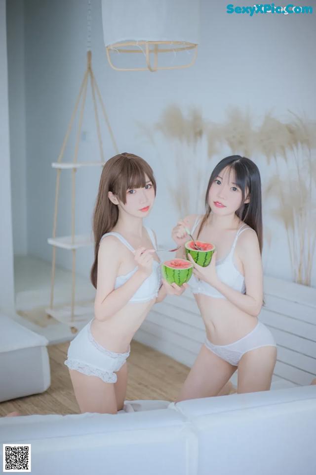 A couple of women sitting on top of a white couch.