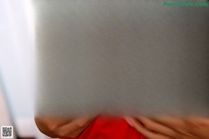 A woman with red fingernails is sitting on a red couch.